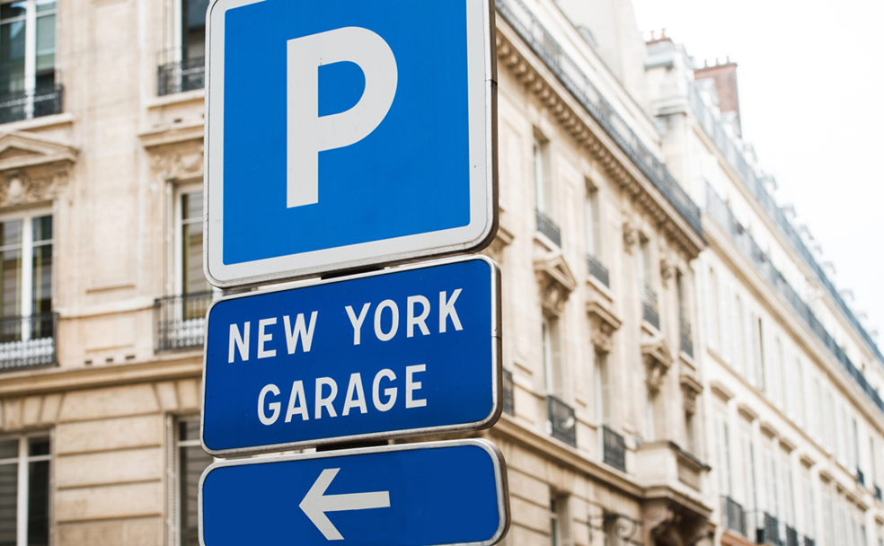 A blue and white sign with an arrow pointing to a new york garage.