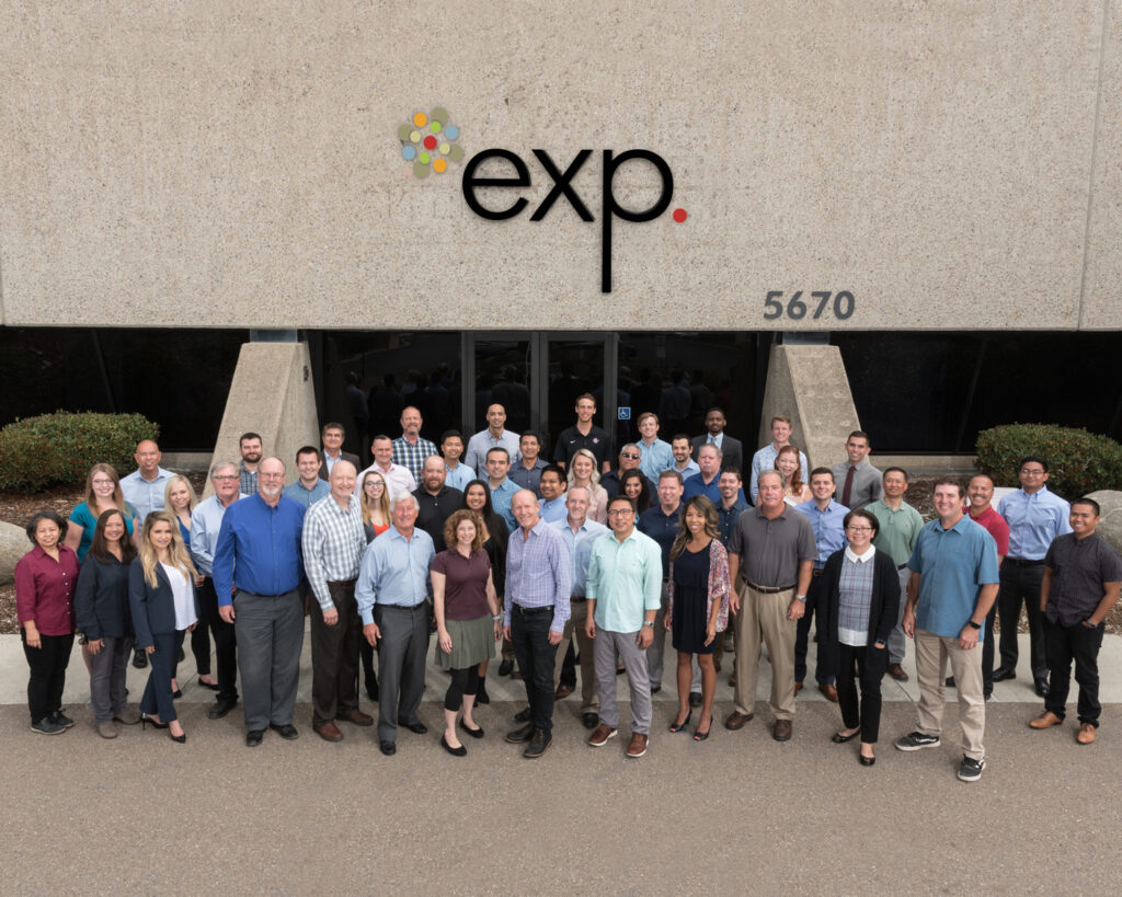 A group of people standing in front of a building with the logo "exp." and the address number "5670" visible above the entrance.