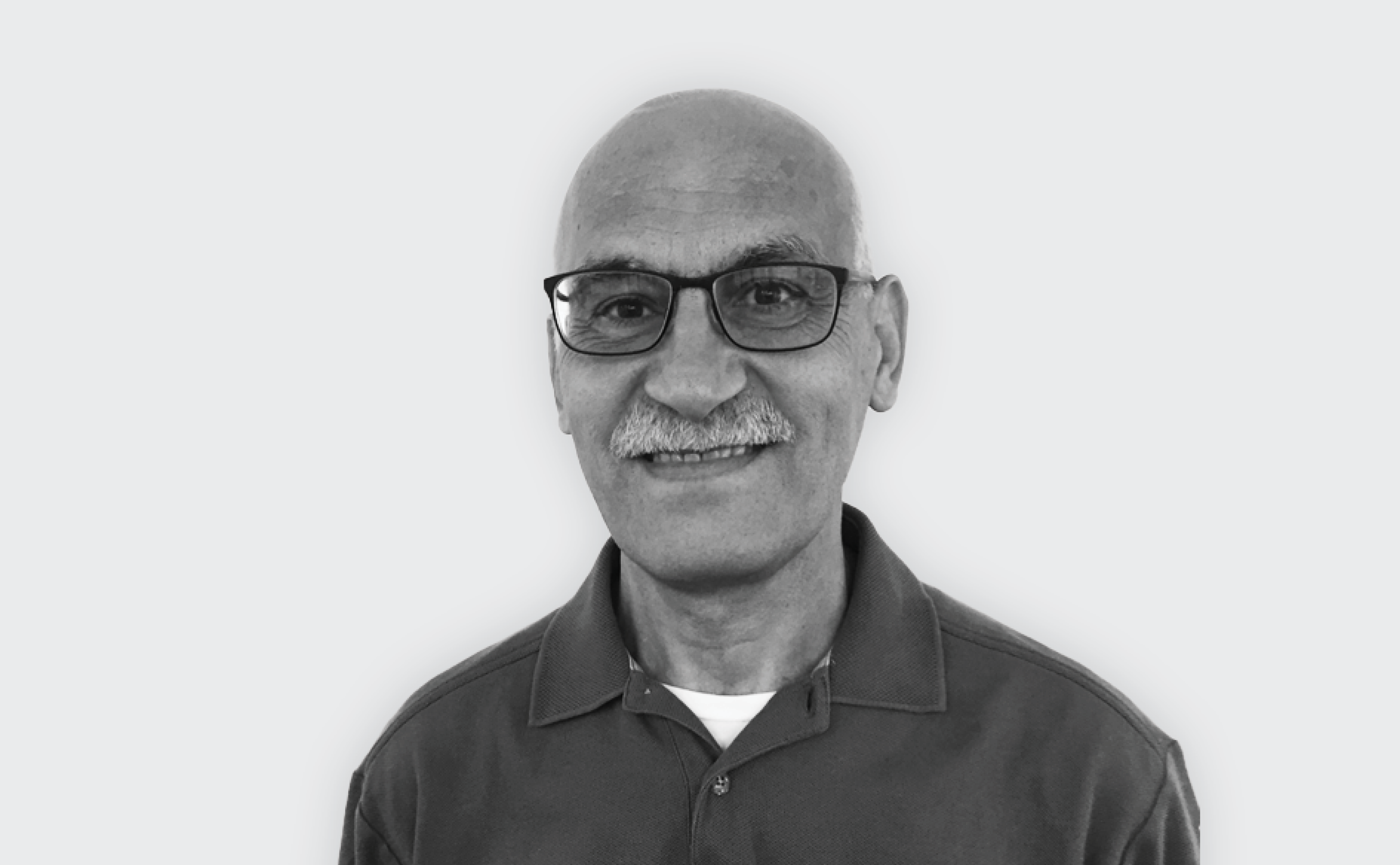 Black and white portrait of a bald man with glasses and a mustache, wearing a collared shirt.