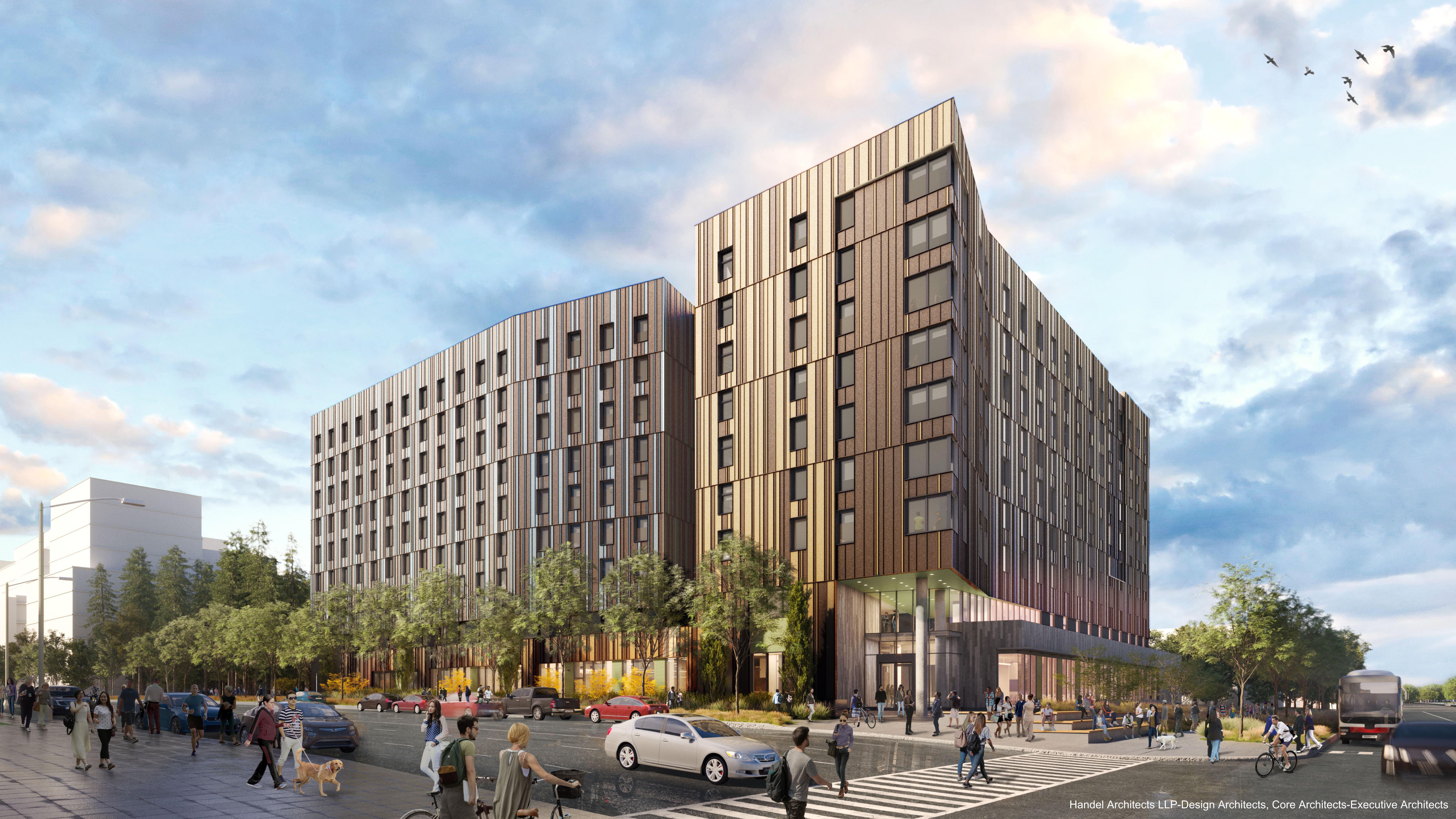 Street view of a modern multi-story building with a wooden facade, large windows, and an entrance at the corner. People are walking on the sidewalk and crossing the street. Cars are parked along the road.