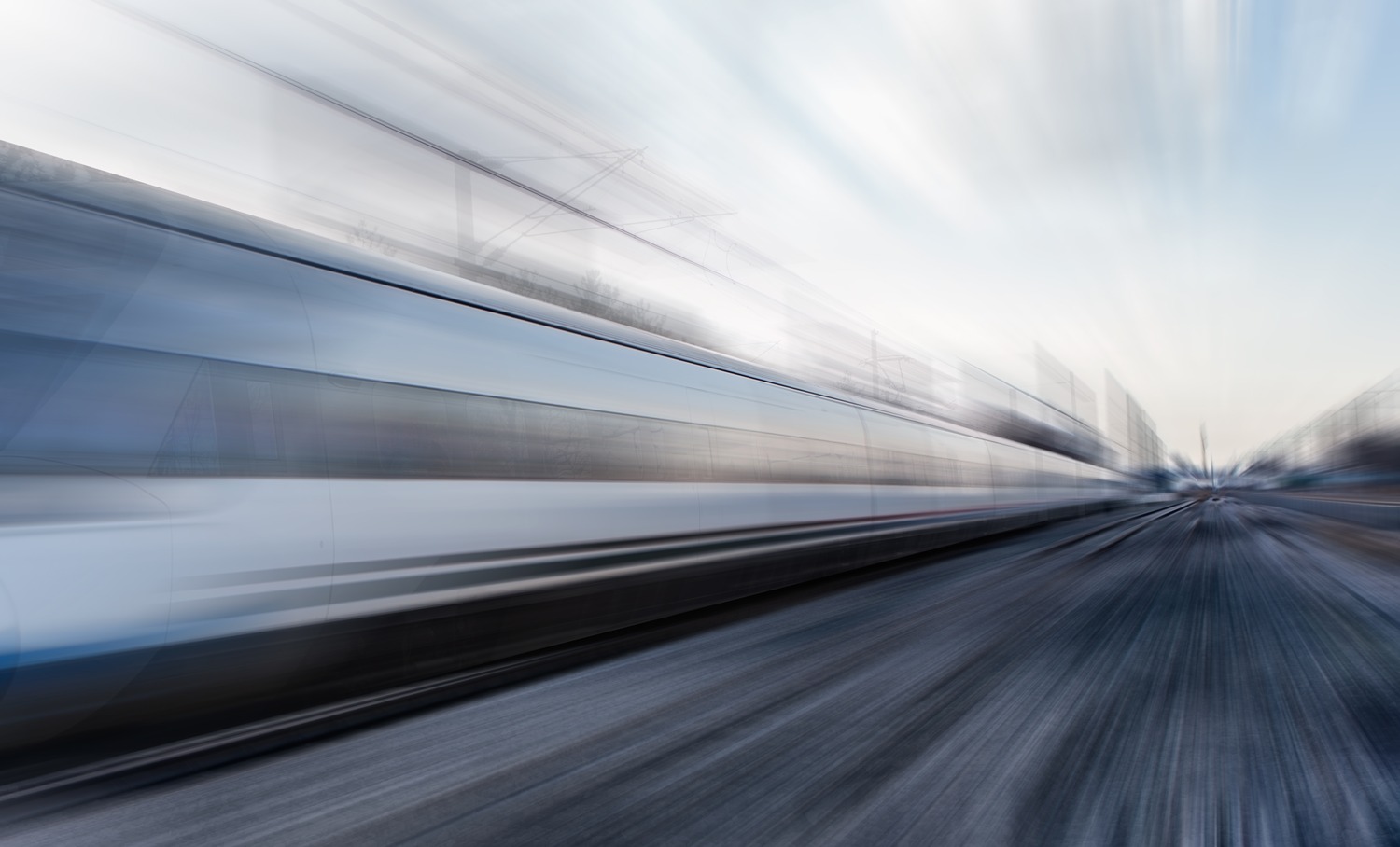 Image floue d'un train à grande vitesse en mouvement, créant une sensation de vitesse et de mouvement le long des voies.