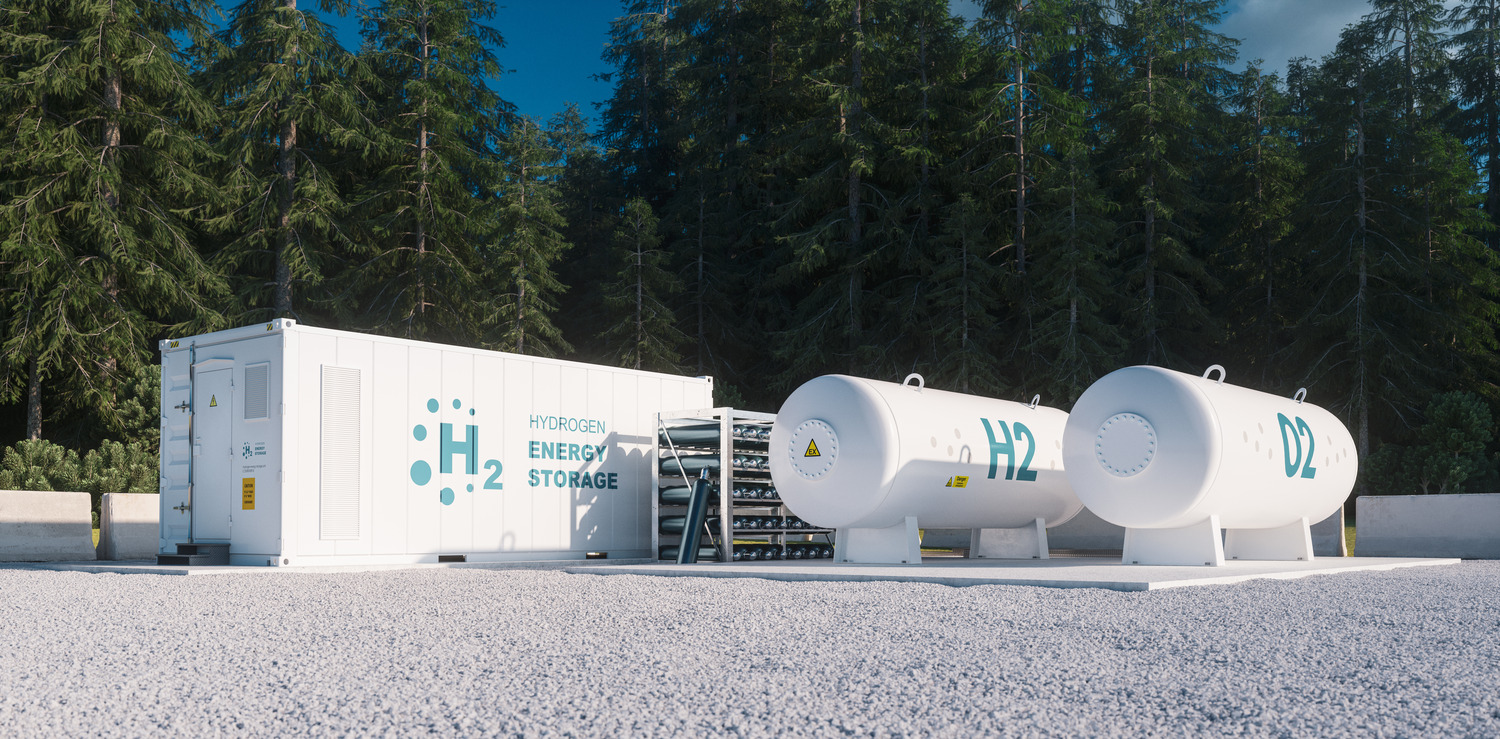 Hydrogen energy storage facility with two large H2 tanks and a control unit, situated outdoors near a forest.