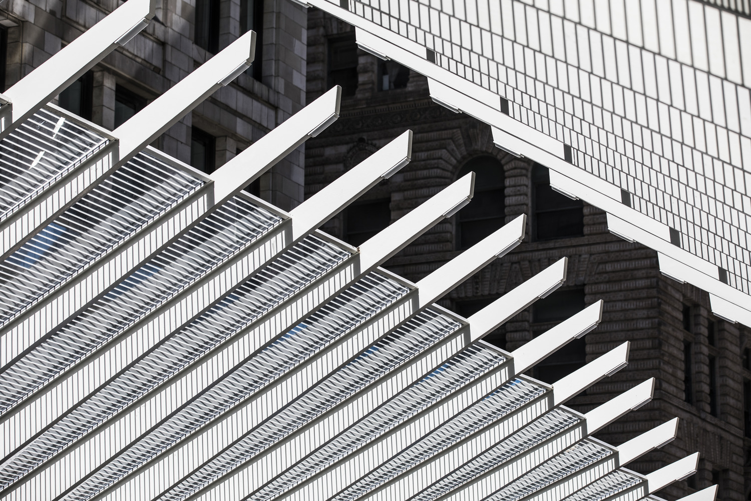 Abstract view of modern architectural structures with overlapping geometric patterns and lines, creating shadows on a building facade.