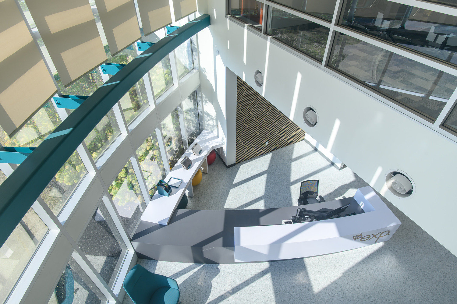 Aerial view of a modern, open office lobby with large windows, curved desk, and minimalist decor.