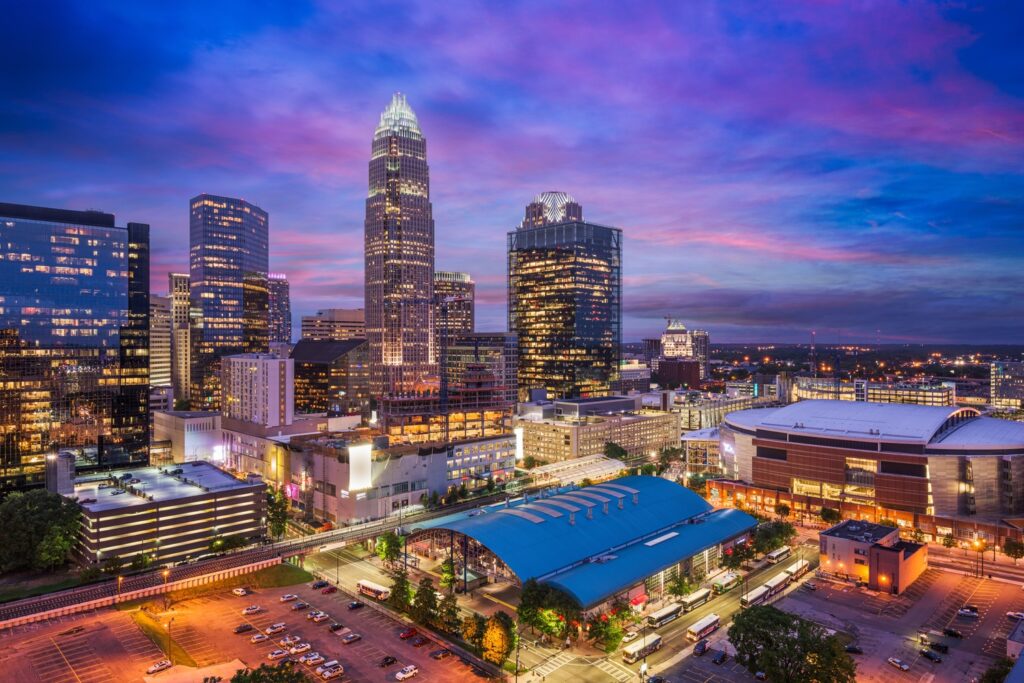 Aerial view of a city skyline at dusk, where lit skyscrapers stand tall against a vibrant purple and blue sky, showcasing the urban facility's embrace of energy efficiency in preparation for NFMT 2025.